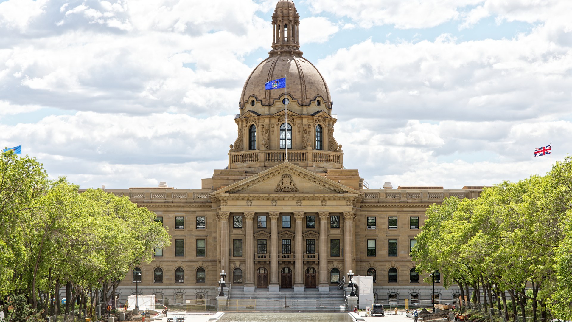 Prédio da Assembleia Legislativa de Alberta, em Edmonton, com a cúpula, a bandeira da província no mastro e árvores dos dois lados da esplanada