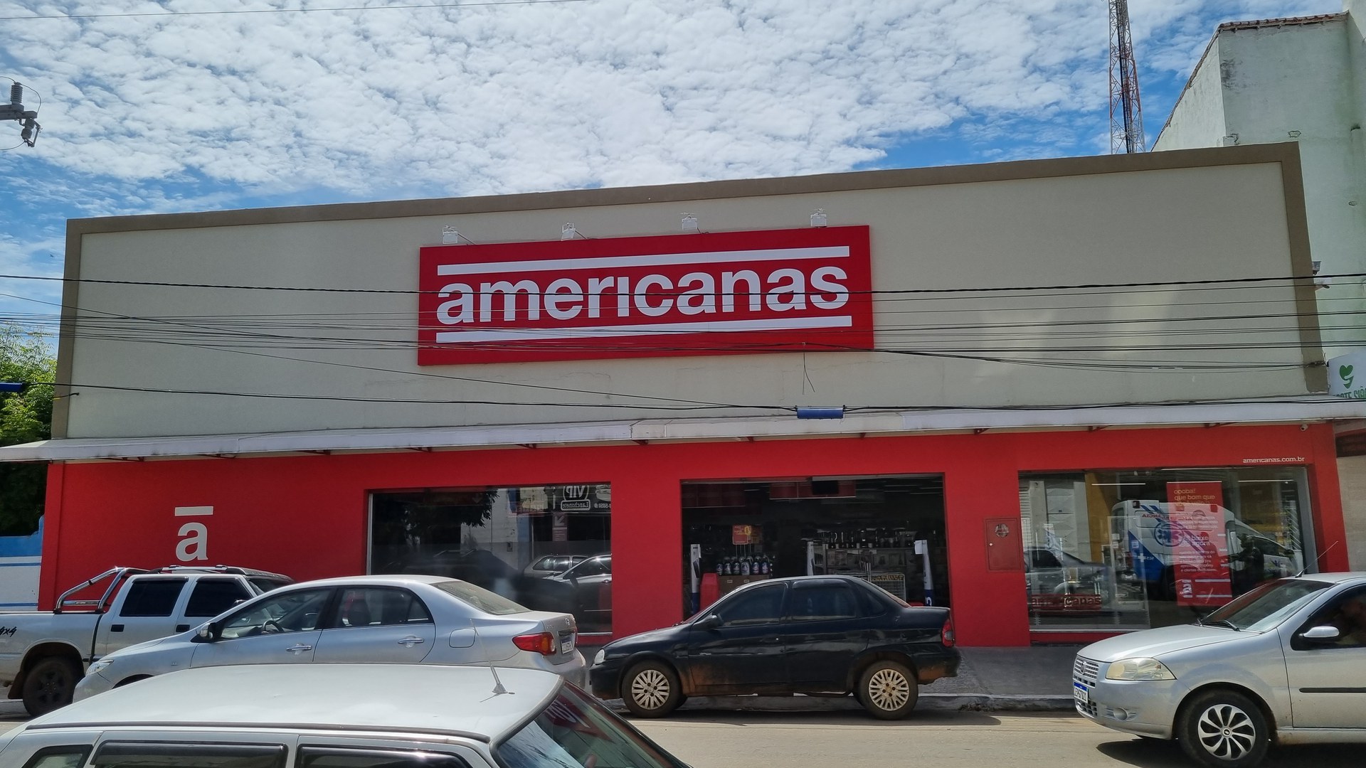 Fachada de uma loja Americanas em Paratinga, na Bahia, com o letreiro vermelho no alto, vitrines de vidro e carros estacionados na rua em frente