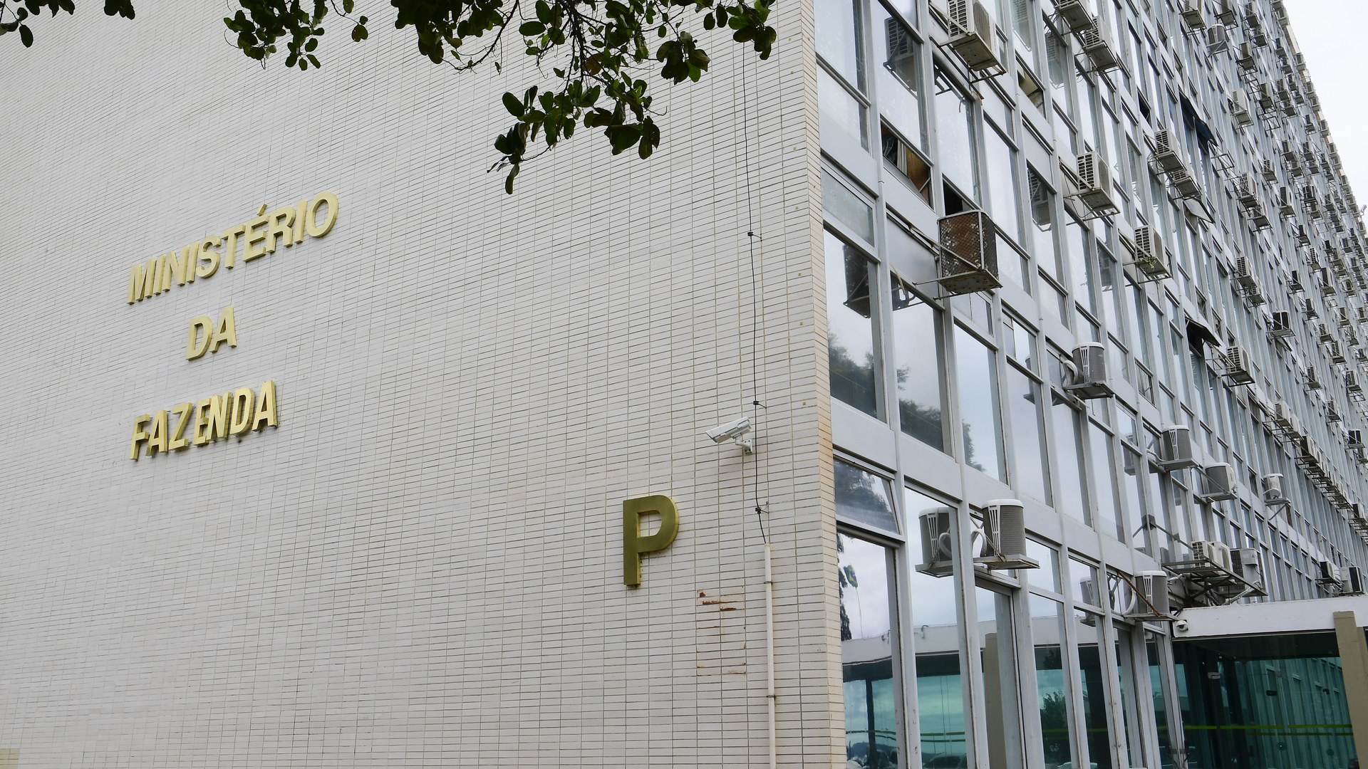 Fachada do prédio do Ministério da Fazenda, em Brasília, com as letras douradas «Ministério da Fazenda» e «P» na parede de pastilhas brancas, ao lado da fachada de vidro com aparelhos de ar-condicionado