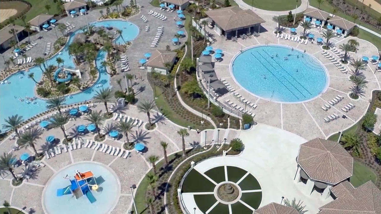 Vista aérea do clube de um condomínio de casas de férias na região de Orlando, com piscinas, rio lento, parque aquático infantil e espreguiçadeiras