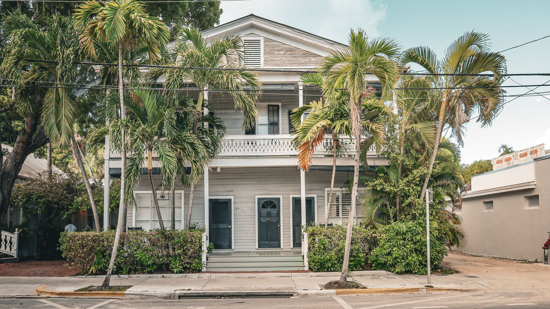 Casa tradicional de dois andares com varandas, cercada de palmeiras, numa rua de Key West, na Flórida