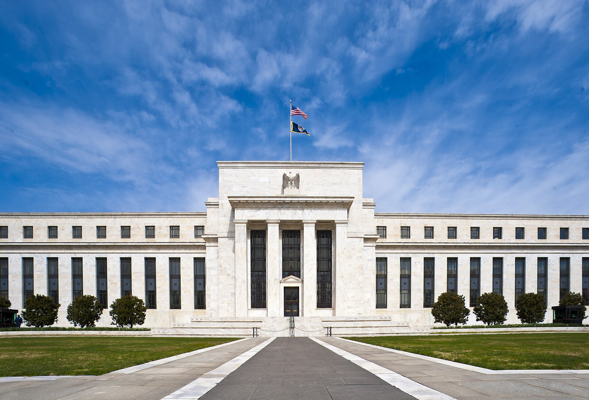Fachada do Edifício Eccles, sede do Federal Reserve em Washington, com as bandeiras dos EUA e do Fed no alto (foto de 2011)