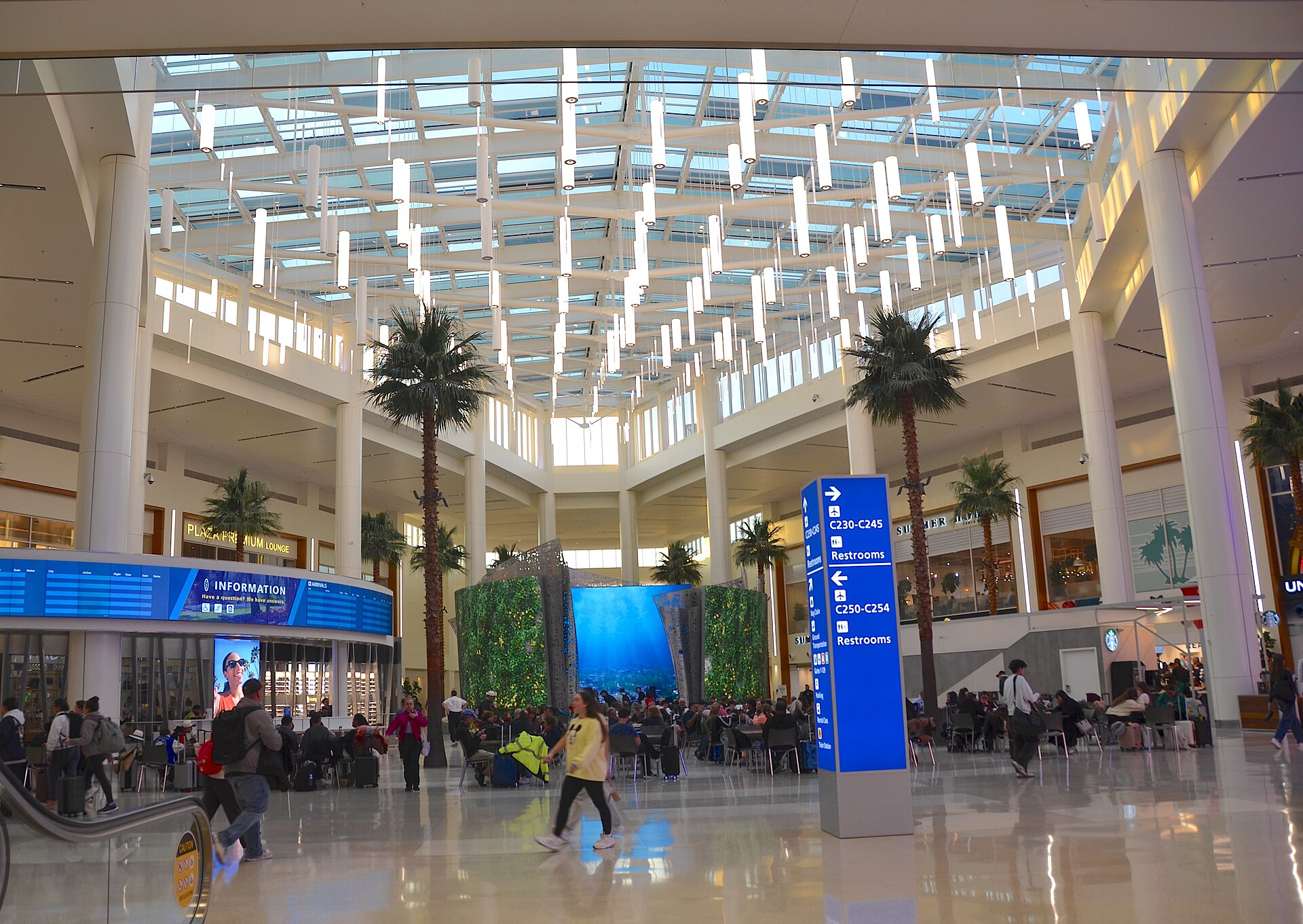 Saguão do Terminal C do Aeroporto Internacional de Orlando, com palmeiras sob a cobertura de vidro e passageiros circulando, em janeiro de 2026
