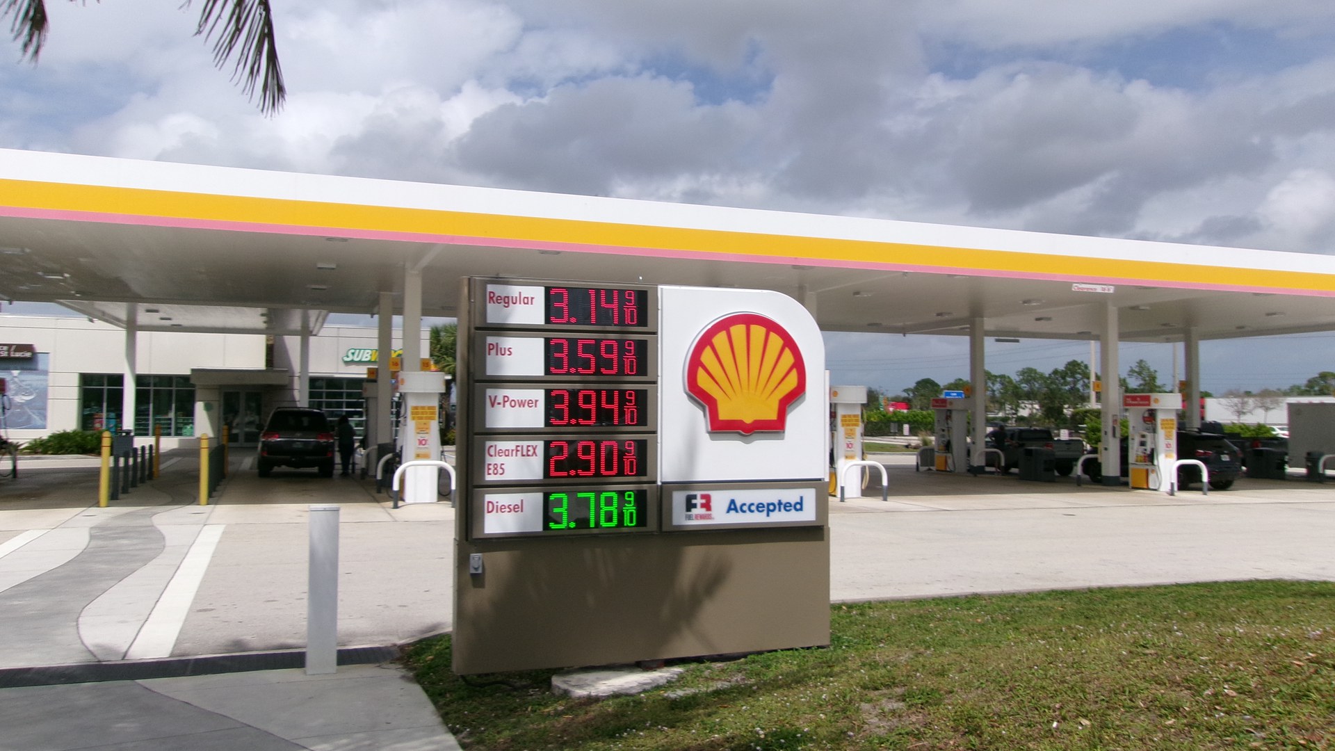 Placa de preços de um posto Shell na área de serviço de Fort Pierce, na Florida's Turnpike, com os preços de março de 2025 em letreiro vermelho e verde e as bombas ao fundo