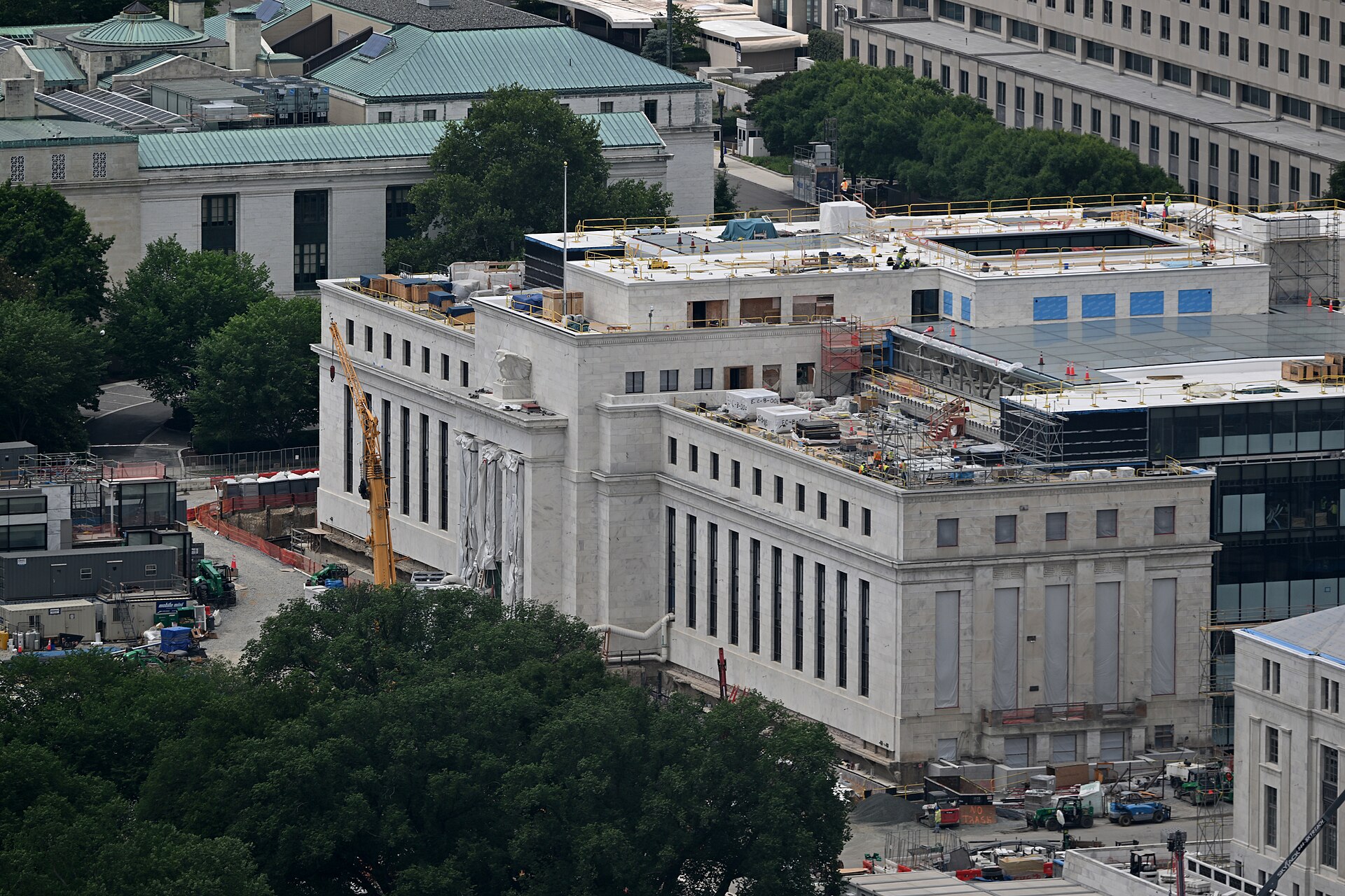 Vista do alto do Edifício Eccles, sede do Federal Reserve em Washington, em obras, com guindaste amarelo, andaimes e operários no telhado (foto de 8 de junho de 2026)