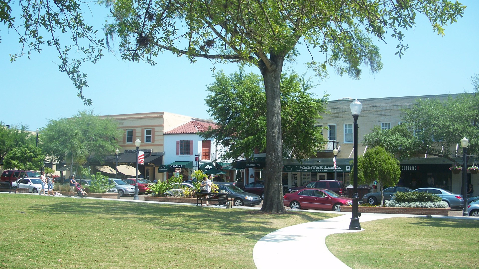 Praça e rua comercial do centro histórico de Winter Park, na Flórida, com lojas, carros estacionados e árvores